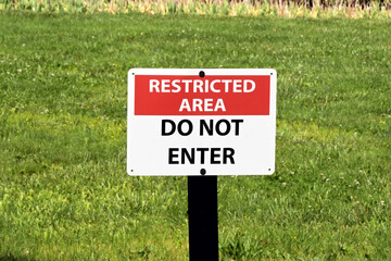Restricted Area warning sign on a lawn with a Do Not Enter message. No people.