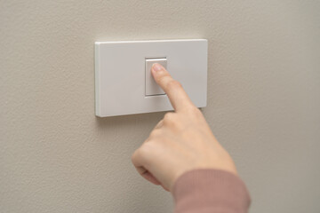 Close up of hand of woman turn off on lighting switch at home room. Finger pushing light switch...