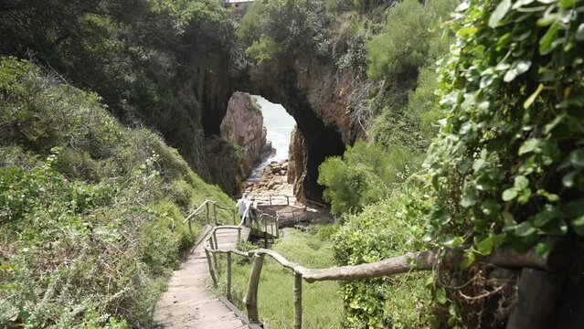 View of hikers on path entering Featherbed sea caves in background in Featherbed Nature Reserve, Knysna, Garden Route, Western Cape Province, South Africa, Africa
