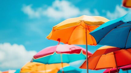 Colorful beach umbrellas against a bright blue sky on a sunny day, capturing the essence of a cheerful summer atmosphere at the coast.