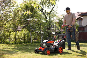Man cutting green grass with lawn mower in garden