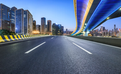 Fototapeta premium Asphalt highway road and bridge with modern city buildings scenery at night