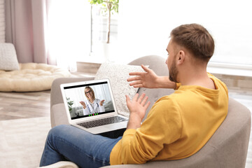 Online medical consultation. Man having video chat with doctor via laptop at home