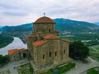 Obraz premium Georgian temple near a river in the green mountains of Georgia - drone photo