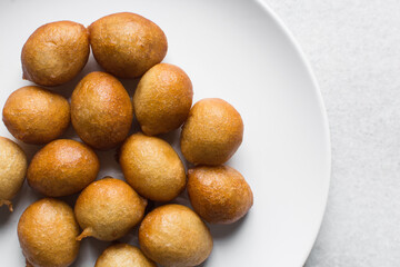 overhead view of nigerian puff-puff on a white plate, flatlay of nigerian fried dough balls, homemade bofrot on white dish
