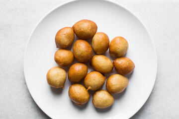 Overhead view of nigerian puff-puff on a white plate, nigerian fried dough balls, flatlay of homemade bofrot on white dish