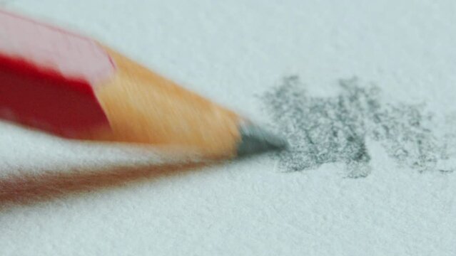 Graphite tip of wood pencil drawing on paper during sketching. Extreme close-up view