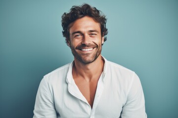 Fototapeta premium Portrait of a smiling man in his 30s wearing a chic cardigan in front of pastel blue background