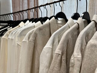 Closeup of linen shirts on hangers in store closet. Closeup of white and beige linen and cotton shirts on hangers in store closet.