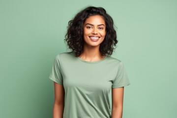 Fototapeta premium Portrait of a satisfied indian woman in her 20s dressed in a casual t-shirt over pastel green background