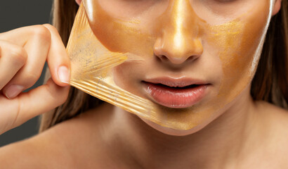 Portrait of a brunette woman who makes a golden mask on her face, neck and collarbones against aging, sagging skin and skin care.Cosmetology concept.