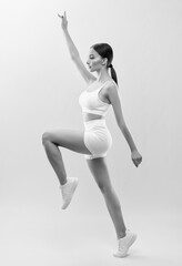 Beautiful attractive girl in white shorts and a top on a black background. The concept of sports and healthy lifestyle.