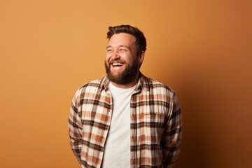 Obraz premium Portrait of a grinning man in his 30s wearing a comfy flannel shirt isolated in pastel brown background