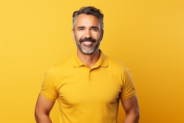 Portrait of a smiling man in his 40s donning a classy polo shirt while standing against soft yellow background