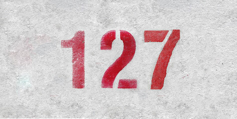 Red Number 127 on the white wall. Spray paint.