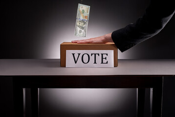 Hand prevents hundred dollar bill from voting box
