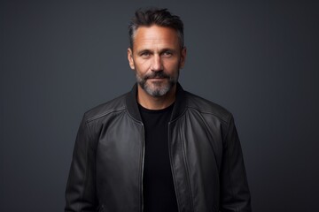 Obraz premium Portrait of a content man in his 40s wearing a trendy bomber jacket over soft gray background