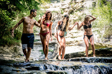 Group of friends having fun at the waterfall. Young group making a wanderlust excursion in the...