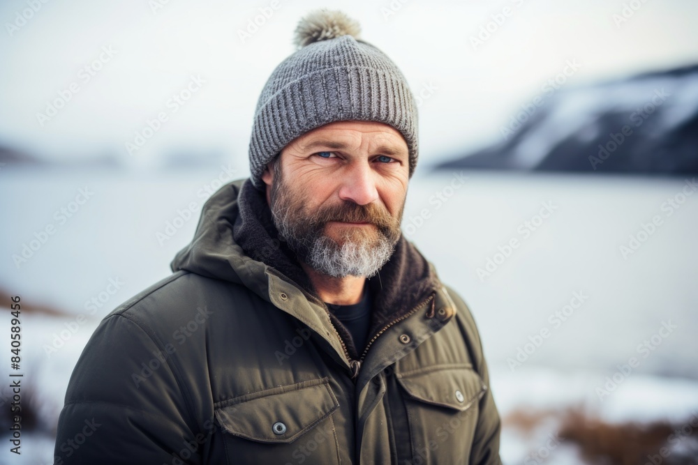 Wall mural Portrait of a tender man in his 40s dressed in a warm ski hat in front of serene seaside background - Wall murals