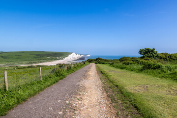 A view along a pathway towards the Seven Sisters cliffs on the Sussex coast, with a  blue sky overhead
