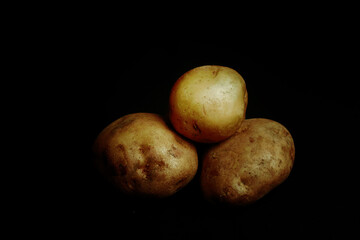 Root vegetables. Fresh fentang. Raw potato diet on black background.