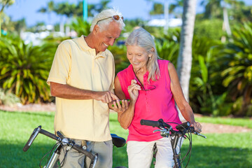 Happy Senior Couple on Bicycles In a Park Using a Smartphone
