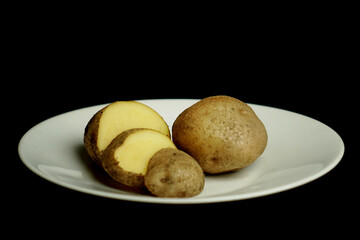 Raw potato diet on black background. peeled potatoes.