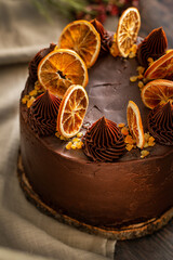 Detail of a chocolate and orange cake beautifully decorated. Chocolate cake decorated with slices of baked orange on a dark brown background. 