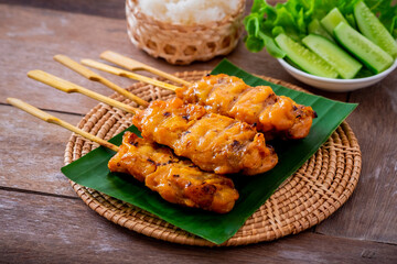 Grilled chicken skewers on banana leaf served with sticky rice and vegetable