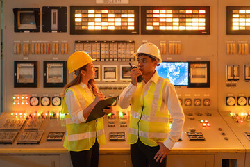 Two Asian male and female engineer executives in the control room of a wind power industry factory for export to regional and global markets and with circuit boards and control switch mechanisms.