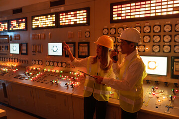 in power plant have two Asian engineers  in a productive brainstorming the production of energy for global distribution, the control room orchestrates the operation of numerous machines and mechanisms