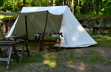 A small cloth tent being a temporary workstation of a blacksmith with all the key tools displayed, including grinder, worktable, anvil, hammer, and other equipment typical for medieval artisans