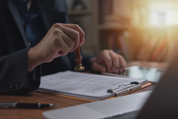 Individual in an office setting applies a stamp to a document contract legal agreement, signifying...