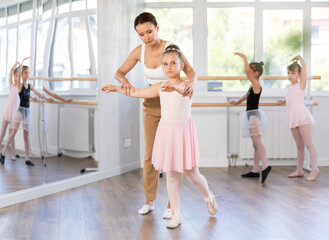 Woman teacher choreographer patiently teaches little girls the basics of ballet and choreography © JackF