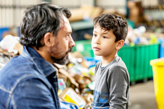 Man teaching a young boy about recycling in an industrial setting.