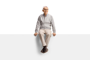 Cheerful elderly man sitting on a blank panel and smiling