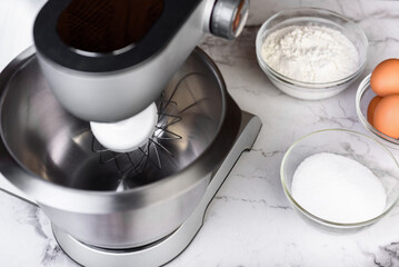 Electric mixer and ingredients for preparing biscuit cake.