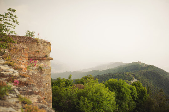Ancient stone wall. View of foggy valley from medieval Forte Sperone. 