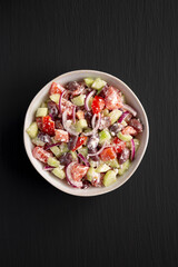 Homemade Chopped Mediterranean Salad in a Bowl on a black background, top view.