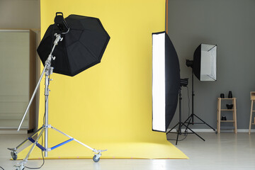 Yellow photo background and professional lighting equipment in modern studio