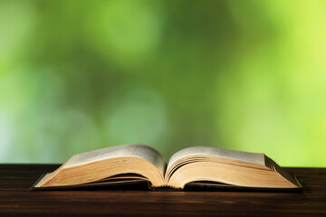 Bible on wooden table against blurred green background, space for text. Religion of Christianity