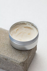  Luxurious body butter in a sleek tin container, elegantly placed on a stone surface. This creamy, nourishing skincare product offers a smooth and hydrating experience, perfect for pampering.