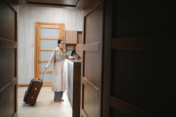 Elegant Business Woman with Travel Trolley Luggage in Hotel Lobby