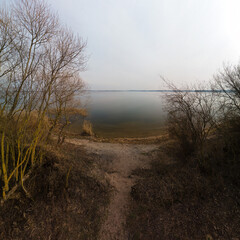 Panaramic view from a height of a flying drone on a spring landscape. Lake and river, field and forest.