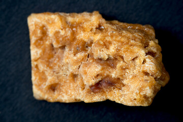 A close-up shot of a square of asafoetida, isolated against a black background.