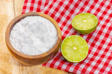 Baking soda in wooden bowl and lemons, on the table