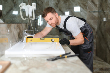 Plumber install sink in bathroom, checks even level of installation. Concept repair service plumbing