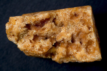An unevenly shaped Asafoetida, captured in a close-up shot, isolated against a black background.