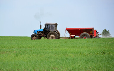 a blue tractor is driving through a field with a red plow