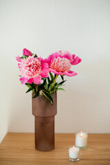 Bouquet of peonies in glass pink vase on wooden table. Spring flowers.